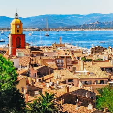 The ochre bell tower over the old town's tiled roofs, the gulf and its hills behind