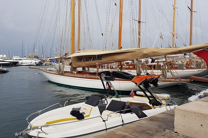 Classic wooden sailing boats with tall masts moored at the quay, a small motor boat in front