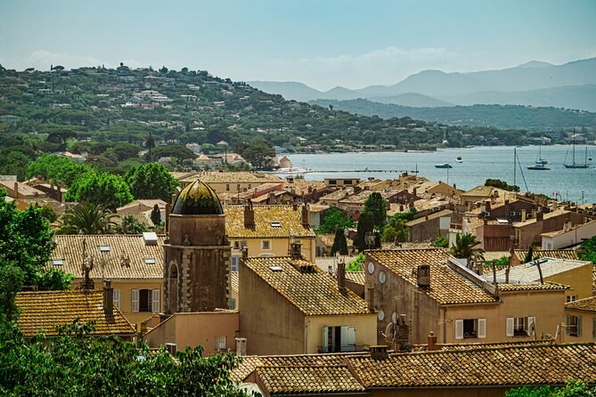 A hill village's roofs and bell tower above the gulf, the mountains behind