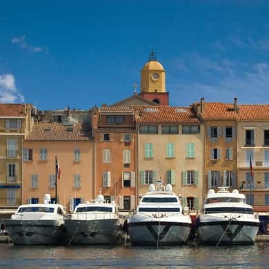 Saint Tropez's harbour front: pastel houses, the ochre bell tower and motor boats moored along the quay