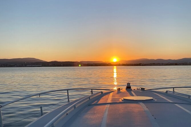 The sun setting over the water, seen from the bow of a moving boat